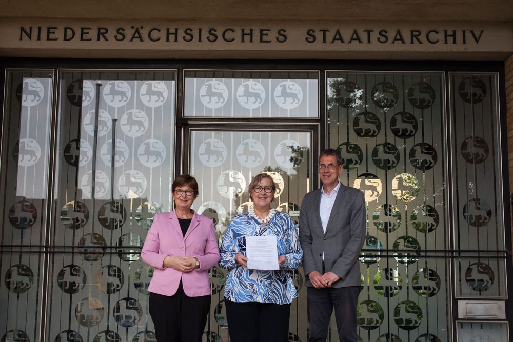 Von links nach rechts: Dr. Sabine Graf (Präsidentin des Niedersächsischen Landesarchivs), Dr. Elke-Vera Kotowski (Moses Mendelssohn Stiftung) und Dr. Brage bei der Wieden (Leiter Niedersächsisches Landesarchiv Wolfenbüttel) stehen vor dem Eingang des Landesarchivs in Wolfenbüttel. Dr. Elke-Vera Kotowski hält die unterzeichnete Kooperationsvereinbarung zwischen dem Archiv und der Stiftung in der Hand. Wolfenbüttel, 20.09.2025 Fotografie: Niedersächsisches Landesarchiv